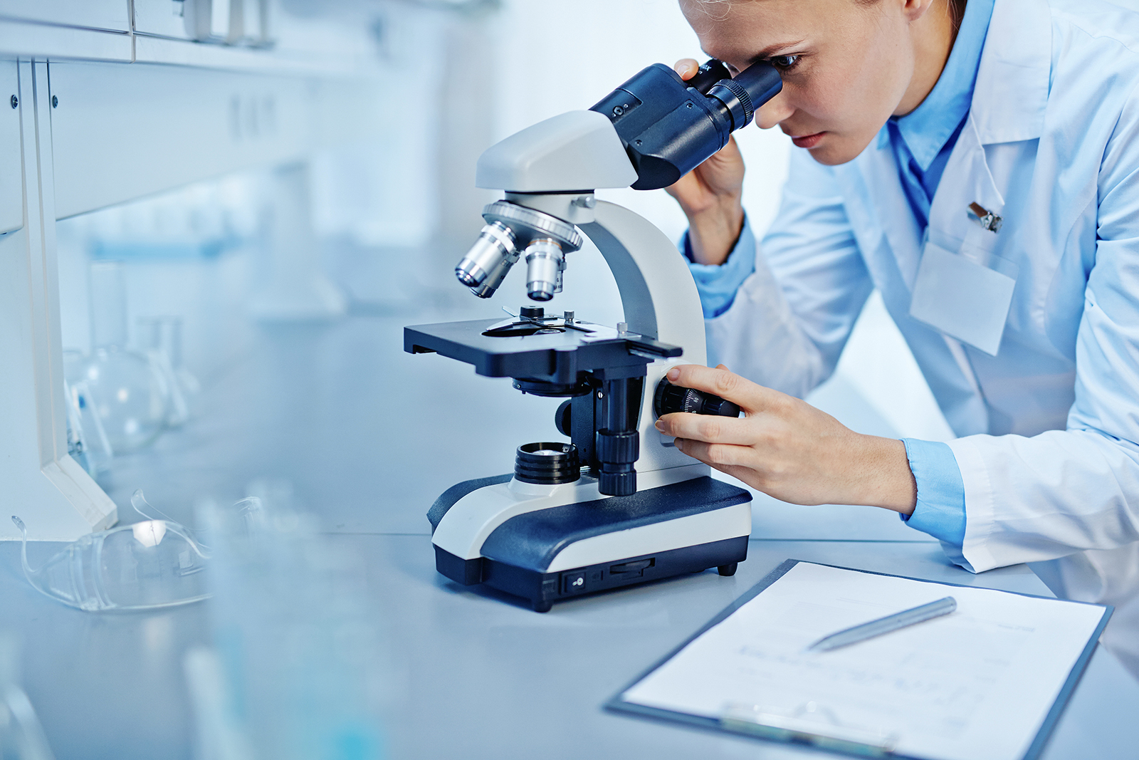 scientist in a lab using a microscope and looking at a slide