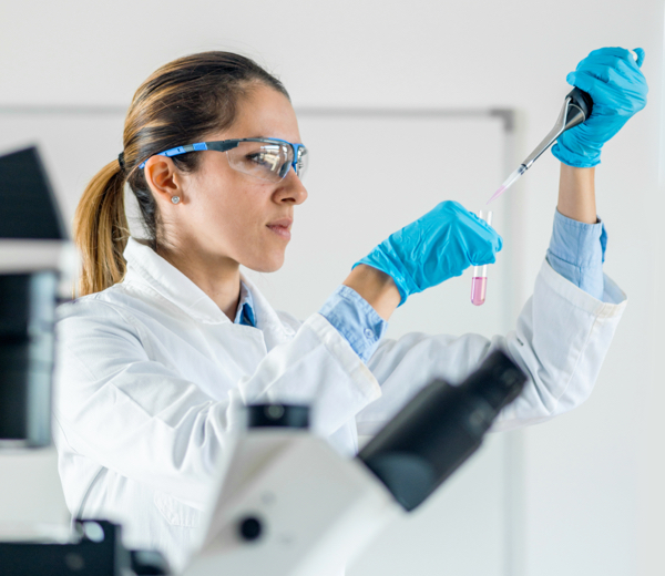 scientist working in a lab with safety goggles on and working with glass test tube